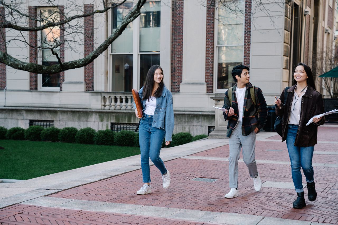 Students walking through a university campus in front of an institutional building