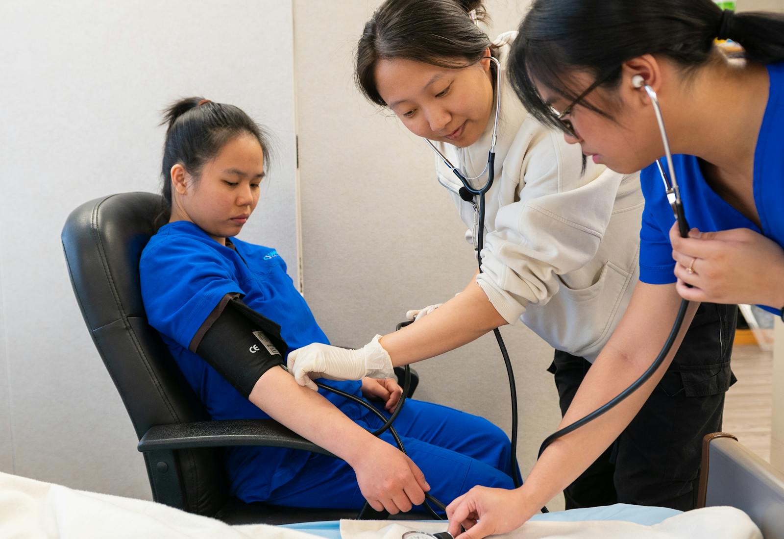 A nursing instructor and student measuring a peer’s blood pressure in a skills lab.