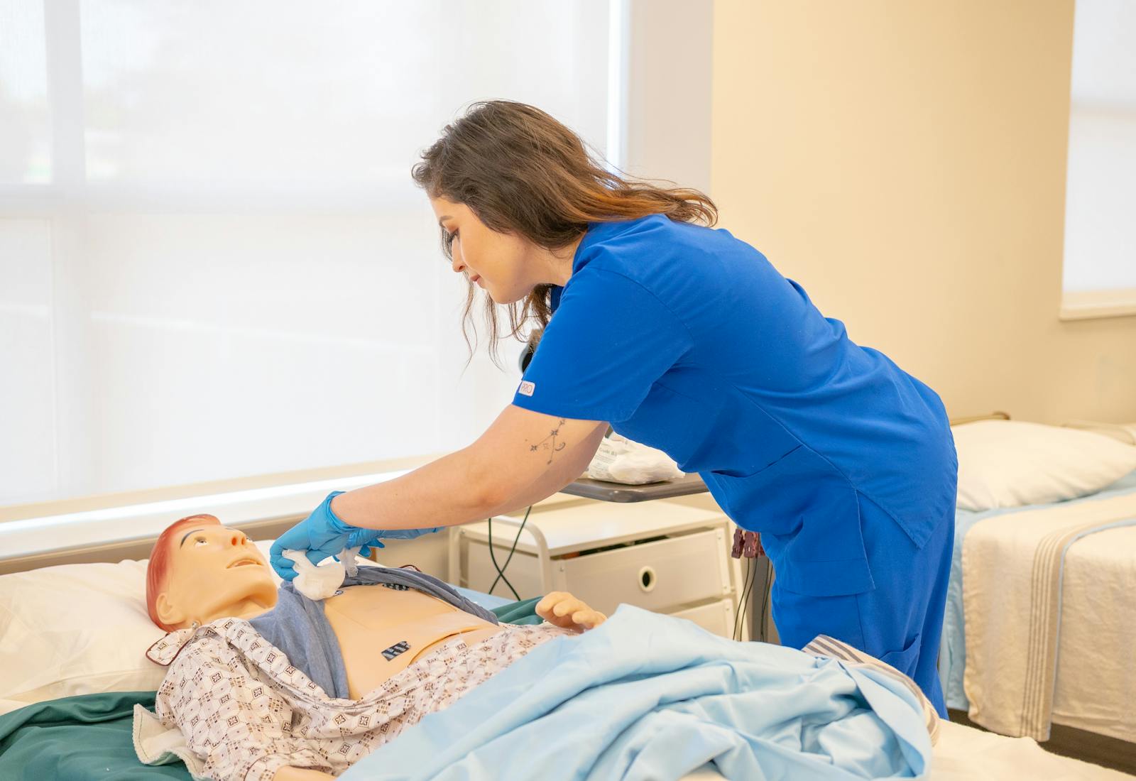 A CNA student practicing a clinical skill on a patient simulation mannequin.