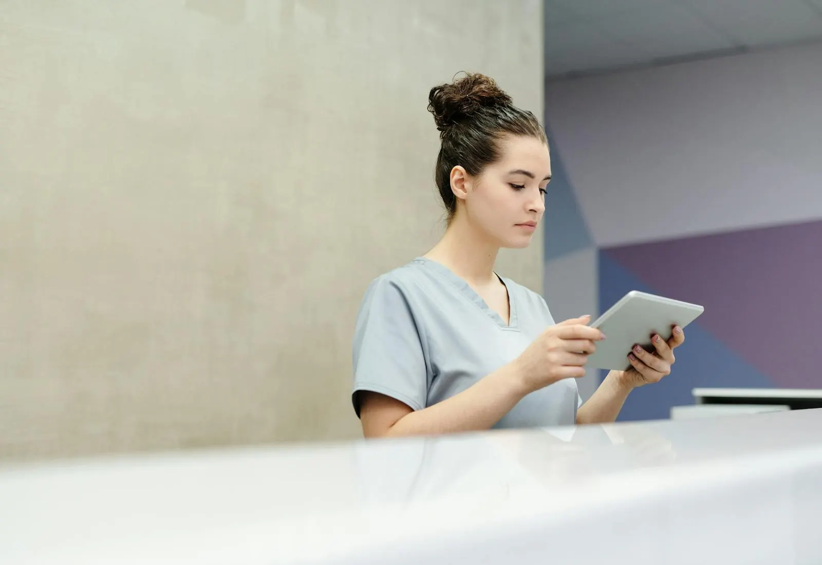 A nurse reviewing records on a tablet at a clinical workstation.