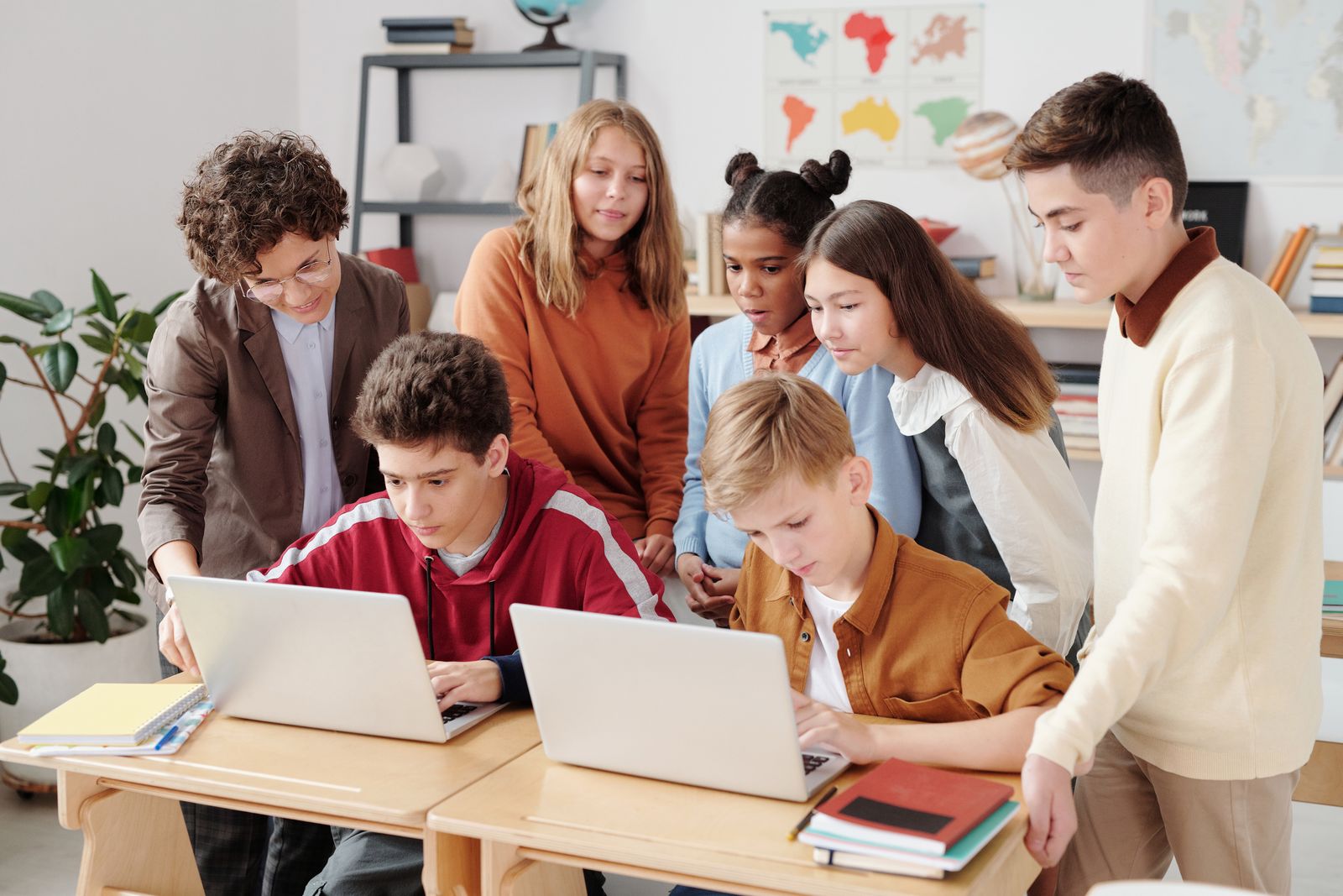 Students learning together on laptops with their teacher.